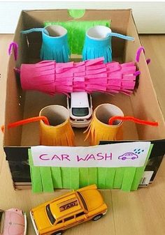 an open cardboard box filled with different types of cars and paper streamers on the floor