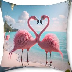 two pink flamingos standing on the beach with their necks in the shape of a heart