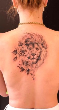 a woman's back with a lion and roses tattoo on it