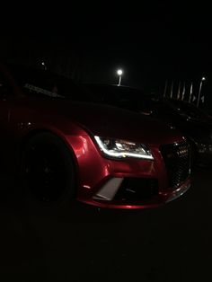 two red cars parked next to each other in the dark