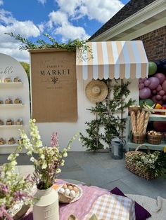 an outdoor market with flowers, baskets and other items on the table in front of it