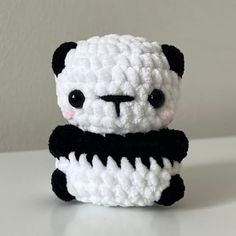 a crocheted panda bear sitting on top of a white table next to a wall