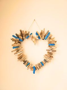 a heart shaped wreath made out of driftwood sticks and blue beads hanging on a wall