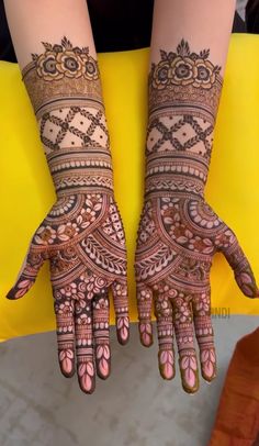 two hands with henna tattoos on them, one is showing the intricate pattern and the other has an elaborate design