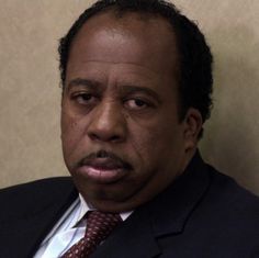 a close up of a person wearing a suit and tie with a serious look on his face