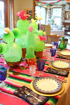 the table is set with colorful plates and cactus decorations