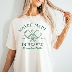 Hello Brides and/or Bridesmaids! For all those loving the pickleball trend this custom Match Made in Heaven Pickleball t-shirt is perfect for you! This Comfort Colors Pickleball inspired bachelorette t-shirt is oh-so-cozy, made from the softest fabric, and you can size up for the trendiest oversized fit! Whether you're the bride-to-be or part of the bridal crew, this tee is the ultimate must-have for your bachelorette party! Throw this tee on while you hit the courts!   Features: 100% ring spun cotton, 30 singles Garment dyed for that lived in feel and almost no shrinkage at home. Soft ring spun cotton fabric with 100% cotton threads Relaxed fit Topstitched, classic width, rib collar Shoulder to shoulder twill tape Signature twill label All sales are final due to customization of product. White Relaxed Fit Top For Tennis, White Relaxed Fit Tennis Top, Summer Tennis Tops With Letter Print, Summer Letter Print Tennis Tops, White Tennis Top With Team Name, Green Graphic Print Tennis Tops, Pre-shrunk Crew Neck Tennis Tops, Perfect Match Pickleball Bachelorette Theme, Pickle Ball Theme Bachelorette