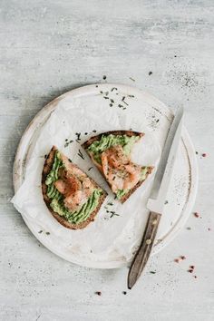 two pieces of toast with avocado and salmon on it next to a knife