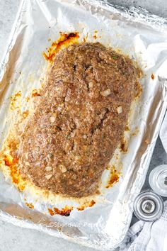 an uncooked meatloaf is sitting on tin foil and ready to go into the oven