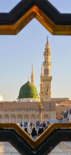 an ornate building with a green dome is seen through a gold and black framed window