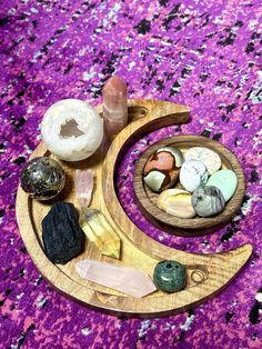 a wooden moon with various rocks and crystals in it on a purple carpeted surface