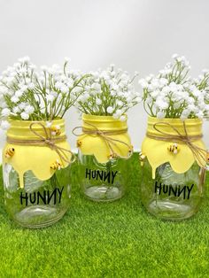 three mason jars with flowers in them sitting on the grass, labeled'hummy'and'honey '