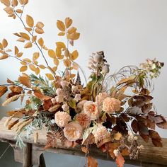 an arrangement of flowers and leaves on a wooden table