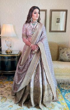 a woman standing in a room wearing a purple and gold lehenga with matching jewelry