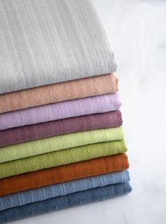 folded towels stacked on top of each other in various colors and patterns, all lined up neatly