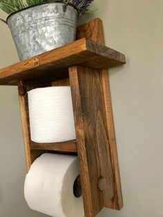 a wooden shelf with two rolls of toilet paper on it and a potted plant