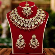 a necklace and earrings set on display in a red velvet case with gold trimmings