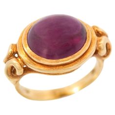 A fantastic Estate rhodolite garnet ring! This 18kt yellow gold piece is bold in size and shape and features a striking rhodolite garnet cabochon at its center. The incredible stone displays a natural reddish-purple color with excellent clarity. A knotted gold bezel setting holds the stone in place, creating a wonderful cut out design that showcases the gemstone beautifully. Finishing the design is a smoothly polished band at the back and stamped inside of the shank is "18k" along with a maker's Luxury Ruby Ring With Oval Cabochon, Luxury Yellow Gold Amethyst Ring Oval Cabochon, Formal Cabochon Domed Ruby Ring, Elegant Yellow Gold Amethyst Cabochon Ring, Elegant Yellow Gold Cabochon Amethyst Ring, Luxury 14k Gold Ruby Cabochon Ring, Fine Jewelry Cabochon Ruby Ring In Yellow Gold, Cabochon Ruby Ring In Yellow Gold, Fine Jewelry Ruby Ring In Yellow Gold With Cabochon