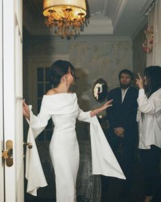 a woman in a white dress is talking to two other people