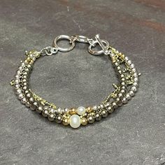 I love a good mixed metals/color combo. :-)   I started with some smooth perfect rounds of both sterling silver and 14kt gold filled beads, tossed in 2 creamy ivory pearls, added some super shiny, top quality pyrite, a hand wrapped 14k gold chain of tiny pyrite dangles, and finished with a pure silver toggle with sizing options at 6.5"; 7"; and 7.5".  Stack it or wear it alone, this is a simple mixed metals piece that can be just as appropriate with jeans and sweater as it is with a dress for a special occasion.   Thanks so much for stopping by today, and for supporting small, artisan, handcrafted goods businesses. 3 Strand Bracelet, Jeans And Sweater, Ivory Pearl, Strand Bracelet, Mixed Metals, Color Combo, Silver Pearls, 7 And 7, 14kt Gold