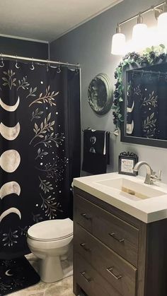 a bathroom decorated in black and white with the moon and stars painted on the shower curtain