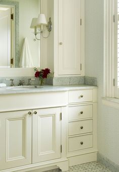 a bathroom with white cabinets and marble counter tops