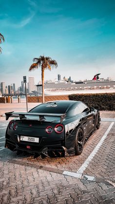 a black sports car parked in a parking lot with palm trees and buildings in the background