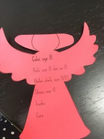 an angel cut out from pink paper on a black table with polka dotes and dots