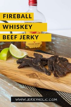 a wooden cutting board topped with pieces of beef next to a bottle of fireball whiskey