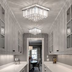 a kitchen with white cabinets and chandelier hanging from the ceiling