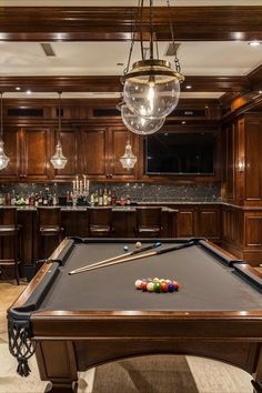 a pool table in the middle of a room with lights hanging from it's ceiling