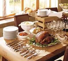 a table set for thanksgiving dinner with turkey and wine glasses