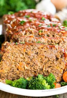 meatloaf on a plate with broccoli and carrots in the background