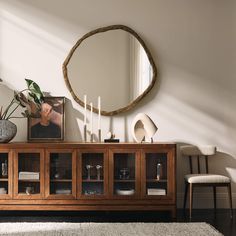 a living room with a large round mirror on the wall and a wooden entertainment center