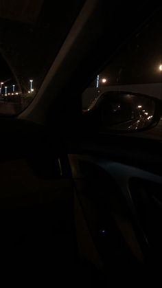 the interior of a car at night with its lights on and streetlights in the distance