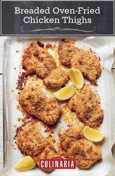 chicken schnitz with lemons and parmesan cheese on a baking sheet