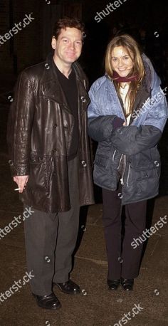 a man and woman standing next to each other in front of a building at night