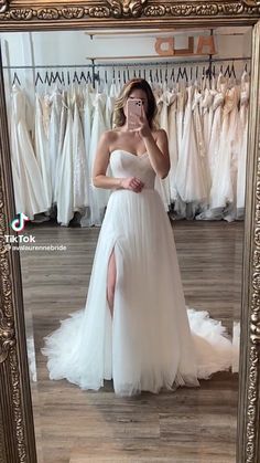 a woman taking a selfie in front of a mirror wearing a wedding dress and high heels