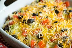 a casserole dish with black olives, tomatoes and cheese