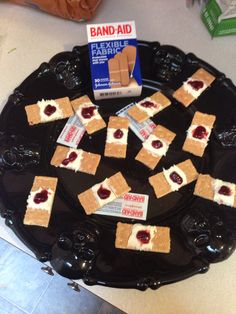 a black plate topped with pieces of cake and marshmallows next to a box of band aid