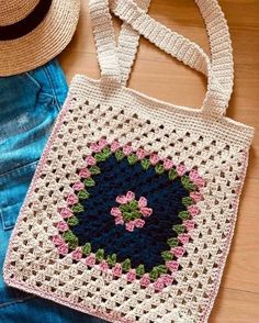 a crocheted bag sitting on top of a wooden floor next to a straw hat