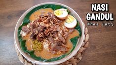 a bowl filled with food sitting on top of a wooden table next to an egg