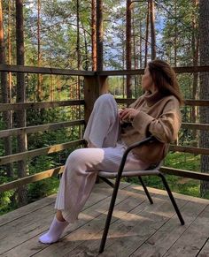 a woman sitting in a chair on top of a wooden deck