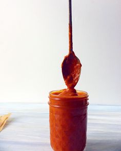 a spoon full of sauce sitting on top of a jar