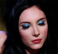 a woman with long black hair and blue eyeshadow is posing for the camera