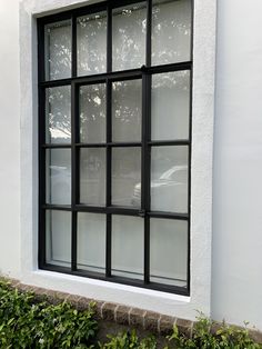 a white building with black windows and green bushes