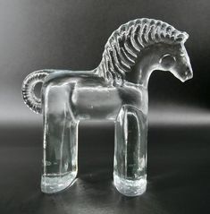 a glass figurine of a horse on a black surface with light behind it