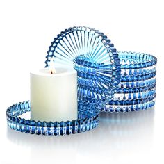 a candle and some blue glass beads on a white surface with a circular object in the middle