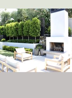 an outdoor living area with white furniture and trees in the backgroung,