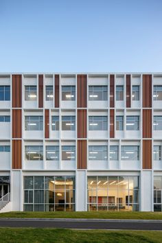 an office building with many windows on the front and side walls, along with grass